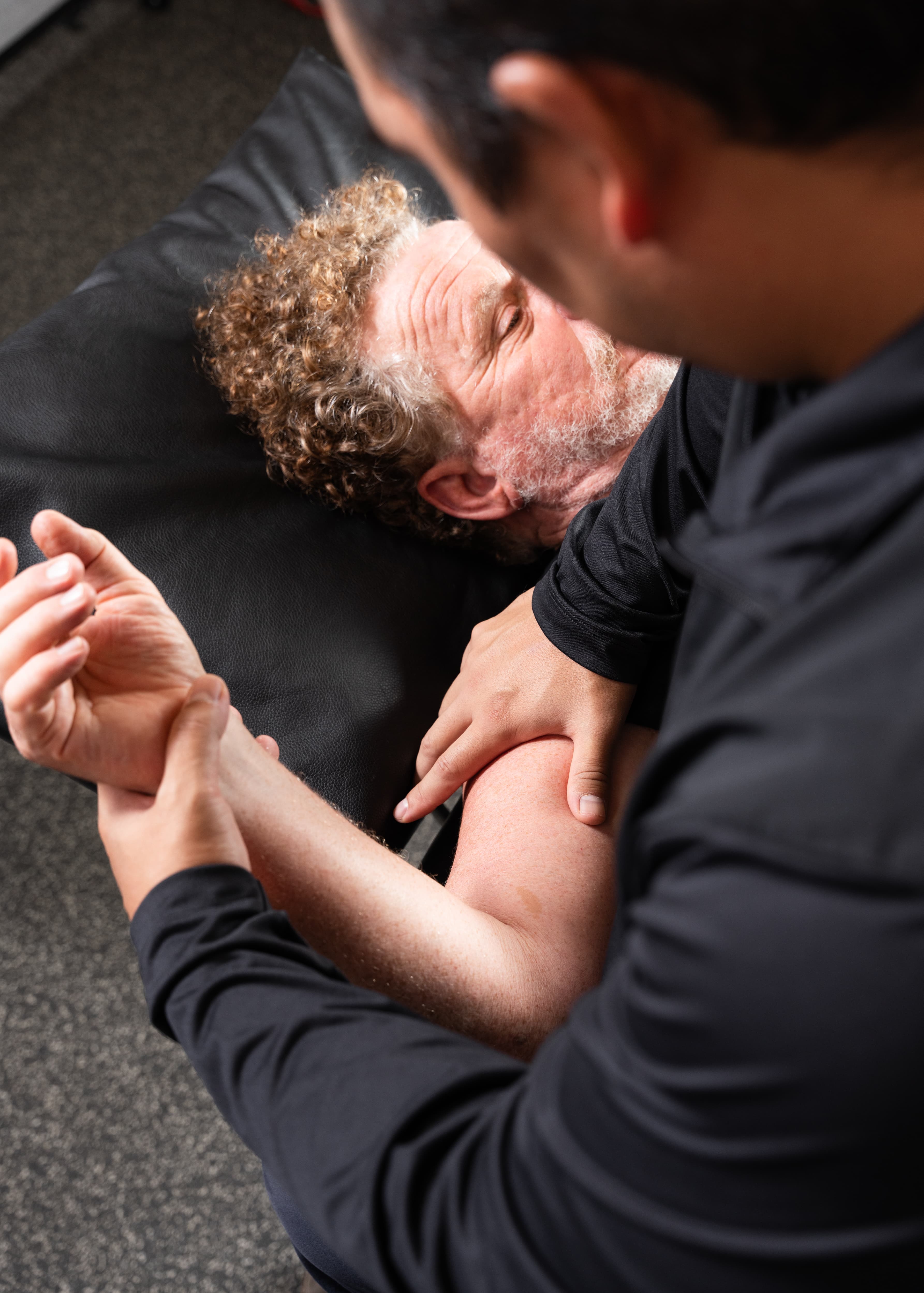 Dr. Jon Sakoda assessing a client's shoulder mobility during a physical therapy consultation